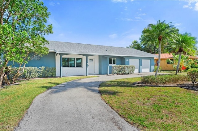 ranch-style house with driveway, stucco siding, an attached garage, and a front yard