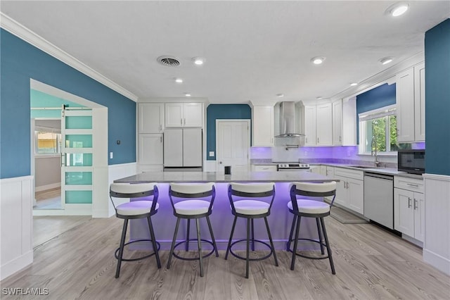 kitchen with visible vents, white cabinetry, a sink, wall chimney range hood, and dishwasher