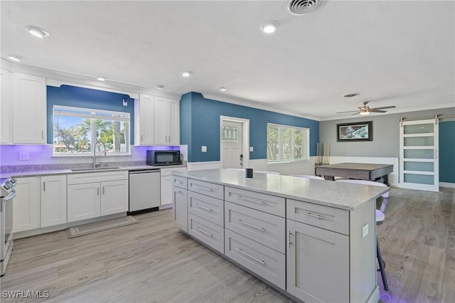 kitchen with a barn door, a sink, visible vents, a center island, and dishwasher