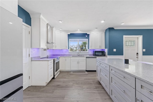 kitchen with range with electric cooktop, freestanding refrigerator, stainless steel dishwasher, wall chimney range hood, and a sink