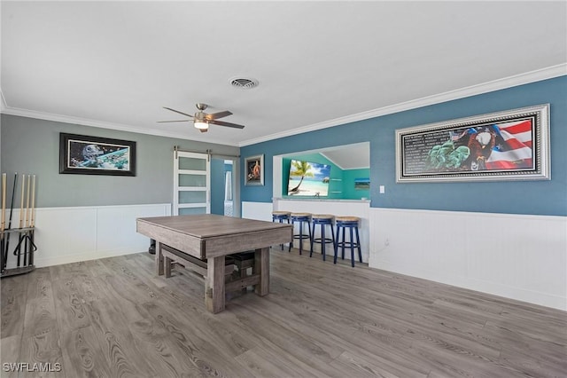 playroom with a barn door, wainscoting, wood finished floors, and visible vents