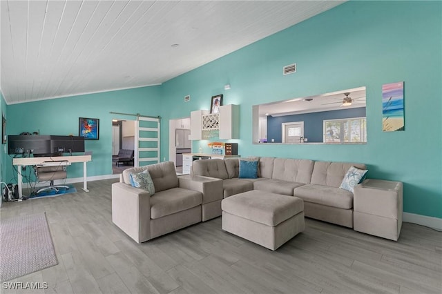 living area featuring a barn door, wood finished floors, visible vents, baseboards, and vaulted ceiling