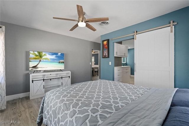 bedroom with a barn door, visible vents, a ceiling fan, baseboards, and light wood-type flooring