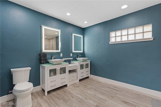 bathroom featuring toilet, baseboards, a sink, and wood finished floors