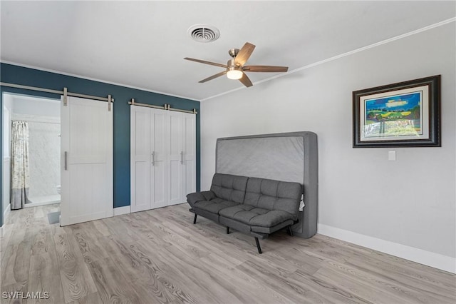 sitting room with a barn door, crown molding, baseboards, and wood finished floors