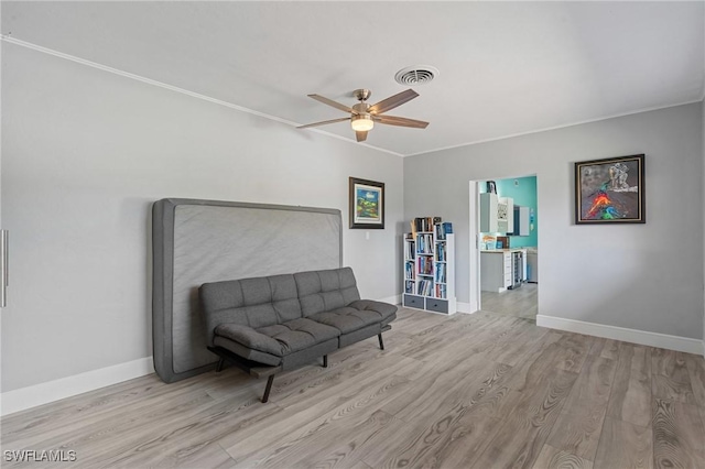 living area with ceiling fan, wood finished floors, visible vents, baseboards, and crown molding