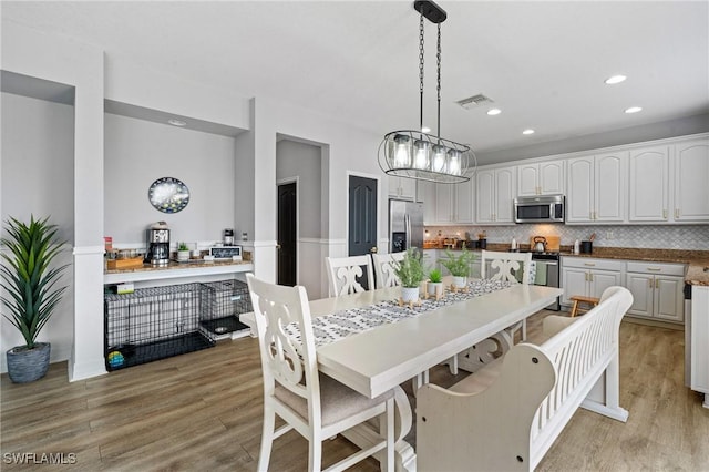 dining space featuring light wood-type flooring, a wainscoted wall, visible vents, and recessed lighting