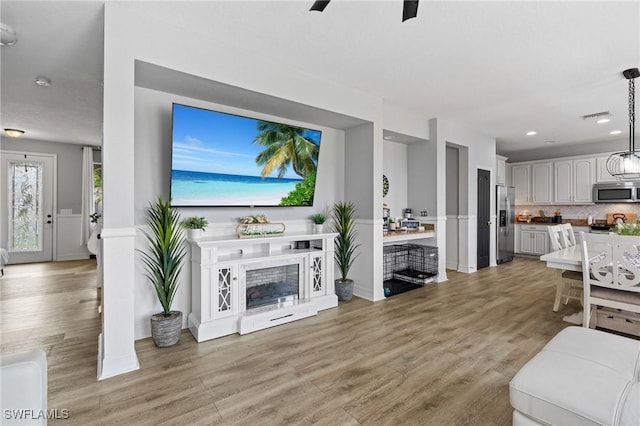 living area with recessed lighting, visible vents, a fireplace, and light wood finished floors