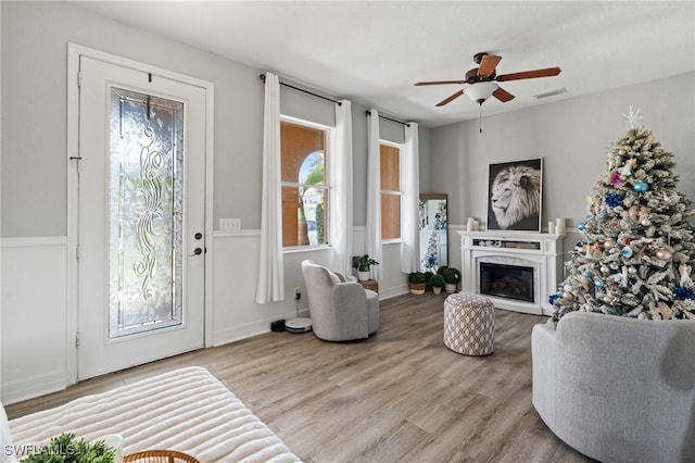 living room with visible vents, ceiling fan, light wood finished floors, and a high end fireplace