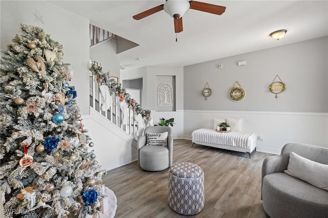 living area featuring ceiling fan, baseboards, and wood finished floors