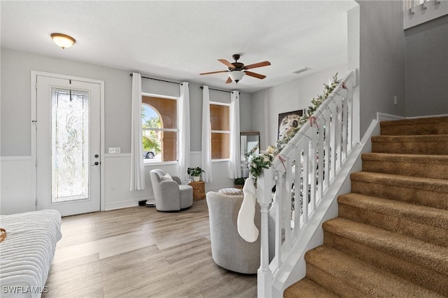 entryway with a ceiling fan, visible vents, light wood-style flooring, and stairs