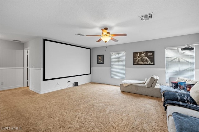 cinema with a textured ceiling, carpet floors, visible vents, and a ceiling fan