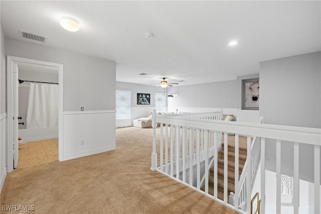 corridor with carpet floors, an upstairs landing, visible vents, and baseboards