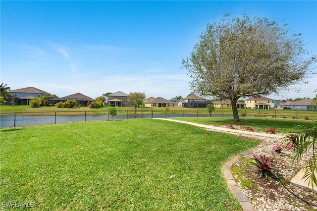 view of yard with a residential view, a water view, and fence