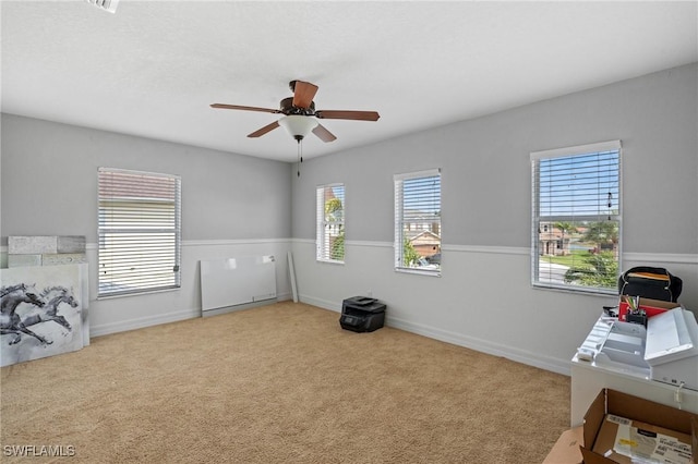 interior space featuring ceiling fan, multiple windows, carpet flooring, and baseboards