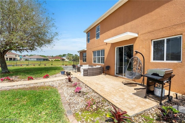 rear view of house with a patio, stucco siding, a lawn, an outdoor hangout area, and fence