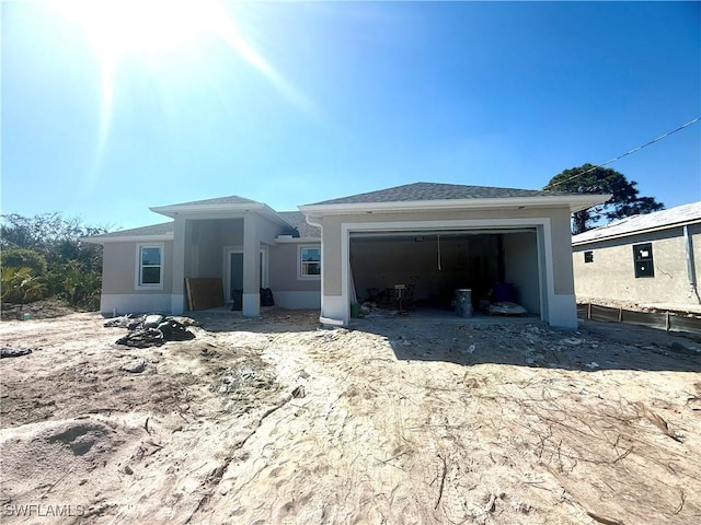 view of front of home with a shingled roof, an attached garage, and stucco siding