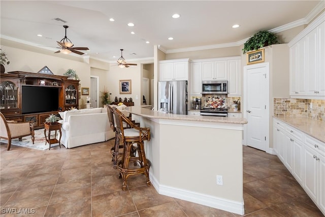 kitchen featuring stainless steel appliances, white cabinetry, open floor plan, ornamental molding, and a center island