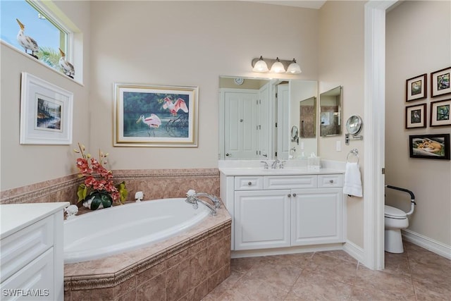 bathroom featuring toilet, vanity, tile patterned flooring, baseboards, and a bath