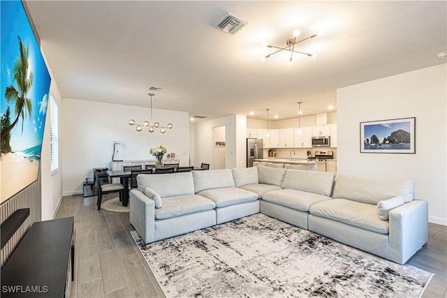 living area with light wood finished floors, visible vents, and baseboards