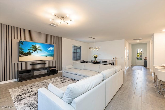 living area featuring wood tiled floor, an accent wall, and visible vents