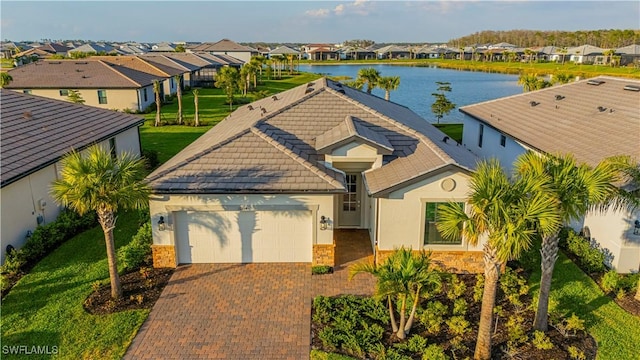 view of front of home featuring decorative driveway, an attached garage, a residential view, and a water view