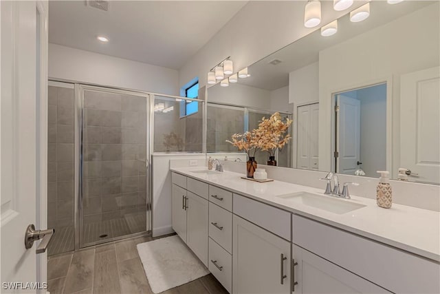 bathroom featuring double vanity, a stall shower, a sink, and visible vents