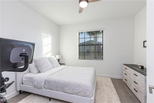 bedroom with ceiling fan, wood finished floors, and baseboards