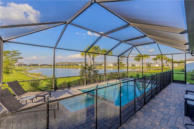 view of swimming pool featuring a patio, glass enclosure, a water view, a pool with connected hot tub, and a yard