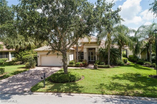 obstructed view of property with decorative driveway, a tile roof, stucco siding, an attached garage, and a front yard