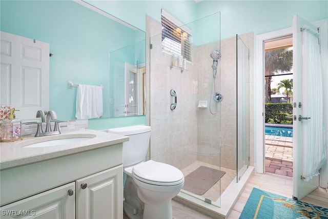 bathroom with a tile shower, vanity, and toilet