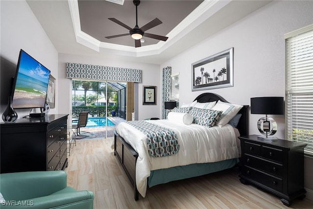 bedroom featuring access to exterior, a tray ceiling, crown molding, and light wood-style floors