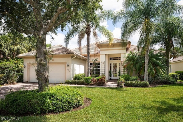 mediterranean / spanish house featuring an attached garage, a tile roof, driveway, stucco siding, and a front lawn