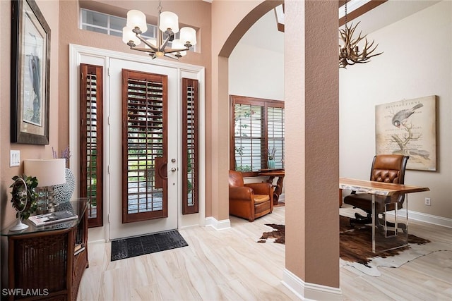 entrance foyer with a notable chandelier, baseboards, arched walkways, and wood finished floors