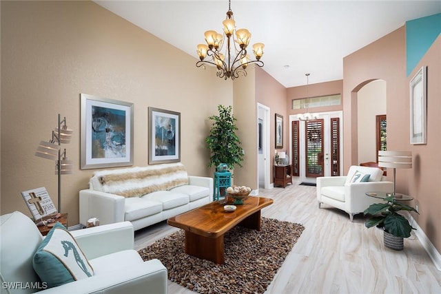 living area featuring arched walkways, wood finished floors, baseboards, and an inviting chandelier