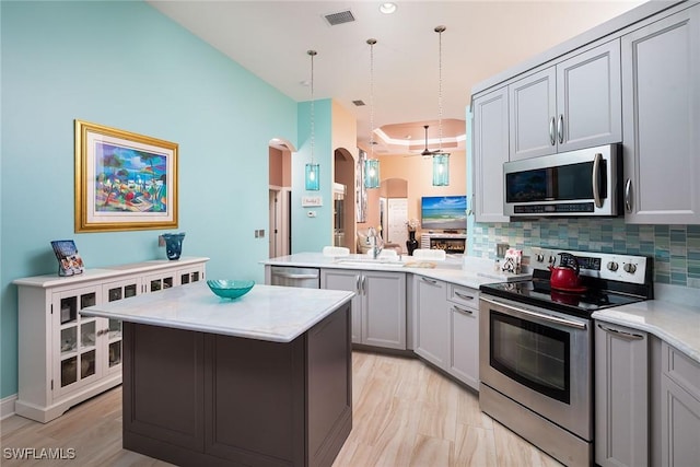 kitchen with arched walkways, gray cabinetry, stainless steel appliances, a peninsula, and visible vents