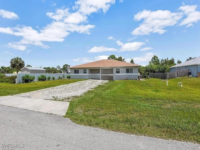 view of front of home with driveway, fence, a front lawn, and stucco siding