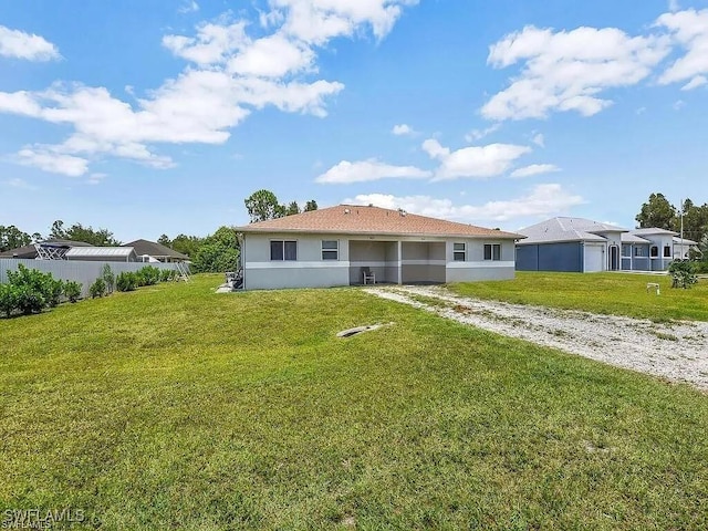 back of property with a yard and stucco siding