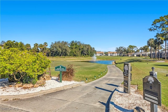 surrounding community with a water view and a lawn