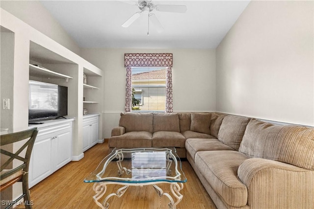 living room featuring light wood-type flooring, ceiling fan, and built in features