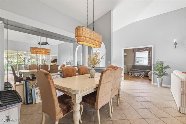 dining room with ceiling fan, high vaulted ceiling, and light tile patterned flooring