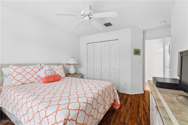 bedroom featuring ceiling fan, dark wood-style flooring, visible vents, baseboards, and a closet