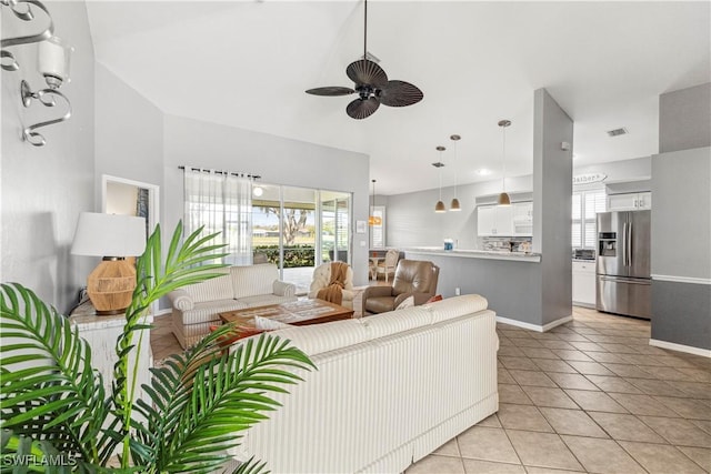 living room featuring a ceiling fan, visible vents, baseboards, and light tile patterned floors