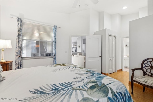 bedroom featuring light wood-style floors, ensuite bath, a closet, and a ceiling fan