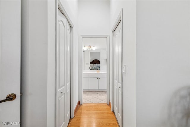 corridor featuring light wood-type flooring and a sink