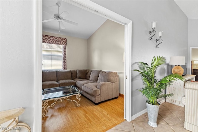 living area with light tile patterned floors, baseboards, vaulted ceiling, and a ceiling fan