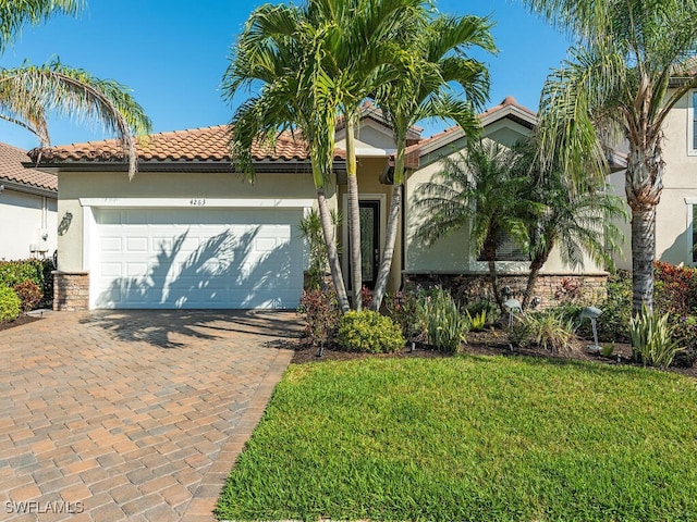 mediterranean / spanish-style house with stucco siding, a tile roof, an attached garage, decorative driveway, and a front yard