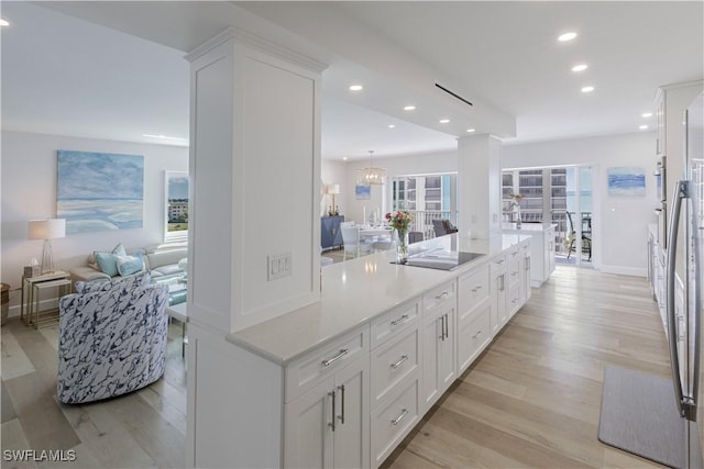 kitchen featuring light wood finished floors, black electric stovetop, open floor plan, recessed lighting, and white cabinetry