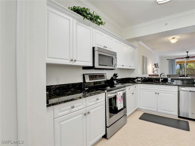 kitchen featuring stainless steel appliances, a sink, white cabinets, dark stone counters, and crown molding