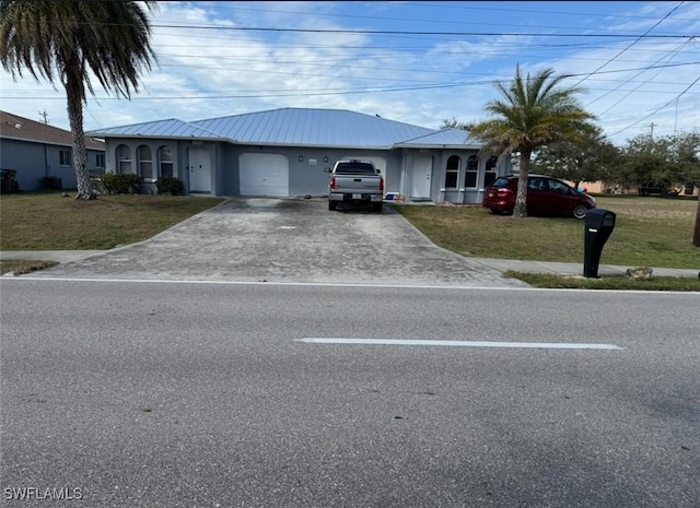 ranch-style home with a garage, metal roof, driveway, and a front lawn